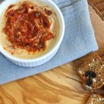 Small dish of creamy hummus with roasted tomatoes stirred into it.
