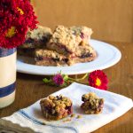A stack of strawberry oatmeal bars on a plate, with one broken apart on a napkin.