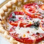 Tomato pie with layers of tomatoes interleaved with cheese, oregano, mayonnaise, salt and pepper.
