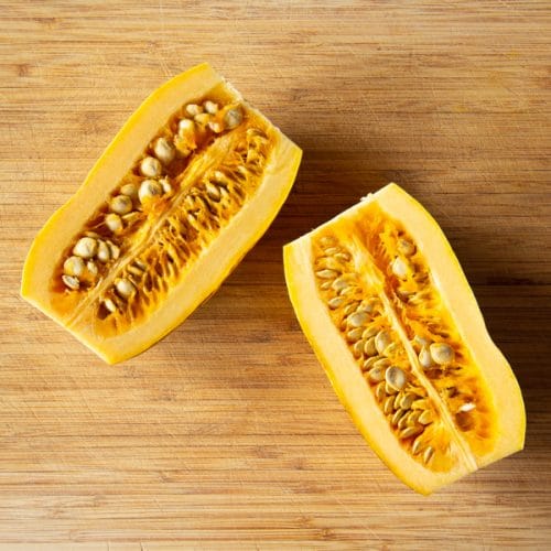 A picture showing how to cut a delicata squash ready to be roasted.
