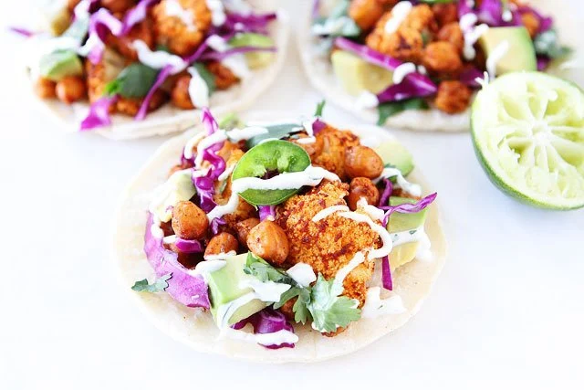 Cauliflower tacos with cabbage, topped with lime crema.