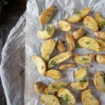Air fryer fingerling potatoes tossed in oil and fresh rosemary on parchment paper.