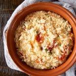 Creamy risotto in a serving bowl with charred roasted tomatoes, fresh basil and Parmesan cheese.
