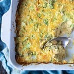 Broccoli cheese casserole with serving spoon scooping out a serving.