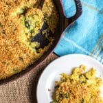 A pan filled with a broccoli cheese casserole and one scoop on a plate.