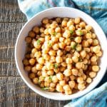 A bowl of cooked chickpeas with some herbs.
