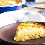 A slice of mac and cheese impossible pie that has a crust, topped with scallions.