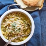 A pot of hearty cauliflower soup with white beans, topped with cheese.