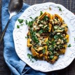 Stuffed Delicata squash with spinach, quinoa, raisins, apples and tofu stuffing, all on a plate.