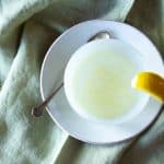 Top view of honey lemon ginger tea, with a lemon wedge on the cup.