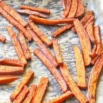 Sweet potato fries on a parchment paper lined baking sheet, fresh from roasting in the oven.