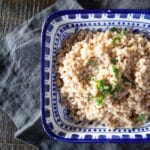 A bowl of cooked barley with chopped parsley on top.