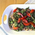 Serving platter of ricotta farro topped with a kale salad and plums.
