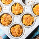 A muffin tin with baked mac and cheese bites with mined jalapeño, and topped with buttered bread crumbs.