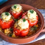 Four stuffed peppers in a baking dish, stuffed with jambalaya rice, beans and cornbread.