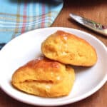 A plate with 2 sweet potato biscuits basted with melted butter.