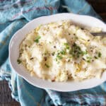 A bowl of colcannon Irish mashed potatoes topped with melted butter, parsley and coarse black pepper.