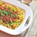A serving dish of lentils and roasted tomatoes on a bed of leeks, celery and carrots.