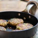 A skillet of quinoa potato patties with spinach.