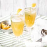 Two glasses of aam panna over ice, with slices of lemon in the background.