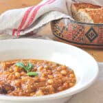A bowl of Moroccan chickpea and eggplant stew, topped with a sprig of mint.