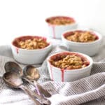 Four mini strawberry rhubarb crisps with 4 spoons.