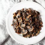 A plate of air fryer mushrooms dusted with Parmesan and fresh thyme.