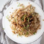 A plate of mujadara topped with caramelized onions and fresh mint.