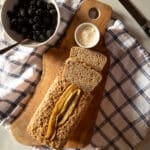 A loaf of banana millet bread with butter and a bowl of berries.