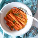 Serving dish of braised citrus ginger carrots with a serving fork.